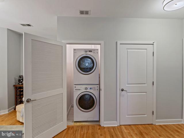 washroom with stacked washer and clothes dryer, laundry area, visible vents, and baseboards