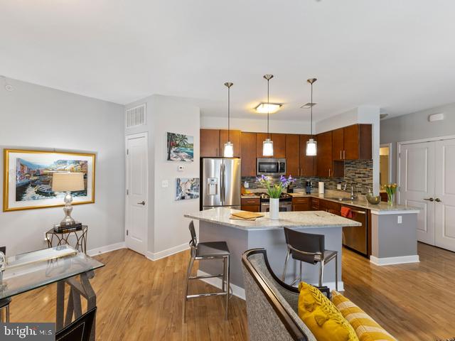 kitchen featuring appliances with stainless steel finishes, baseboards, a sink, a kitchen bar, and light wood-type flooring