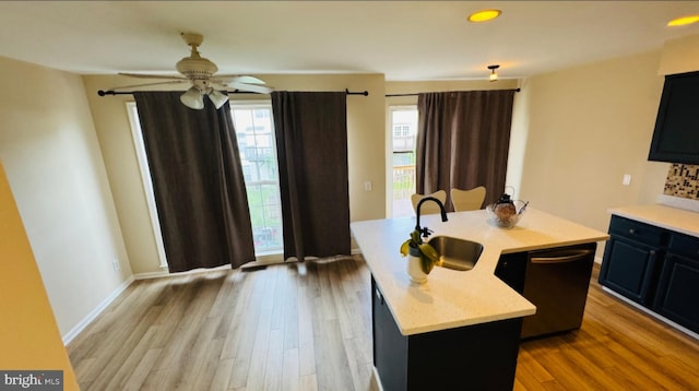 kitchen with a sink, a center island with sink, wood finished floors, and a ceiling fan