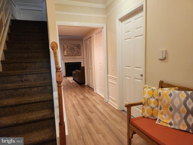 stairs featuring wood finished floors, crown molding, and a fireplace