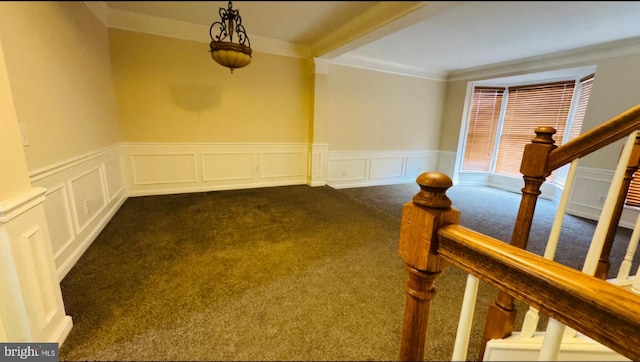 unfurnished room with dark colored carpet, a decorative wall, ornamental molding, wainscoting, and stairway
