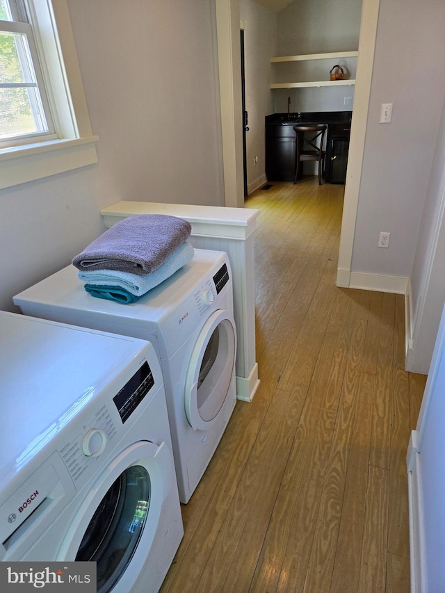 laundry room with washing machine and dryer, laundry area, baseboards, and light wood-type flooring