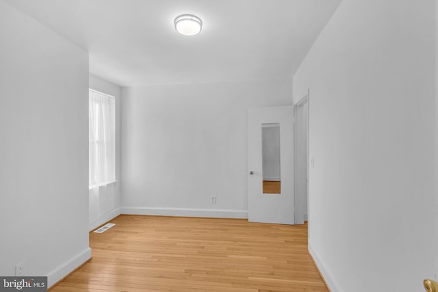 spare room featuring light wood-type flooring and baseboards