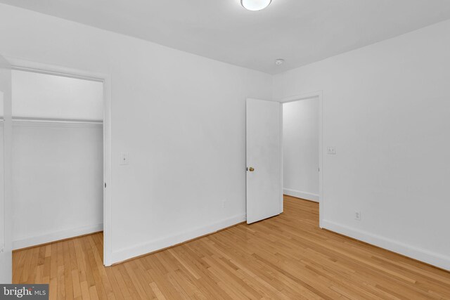 unfurnished bedroom featuring wood finished floors, a closet, and baseboards