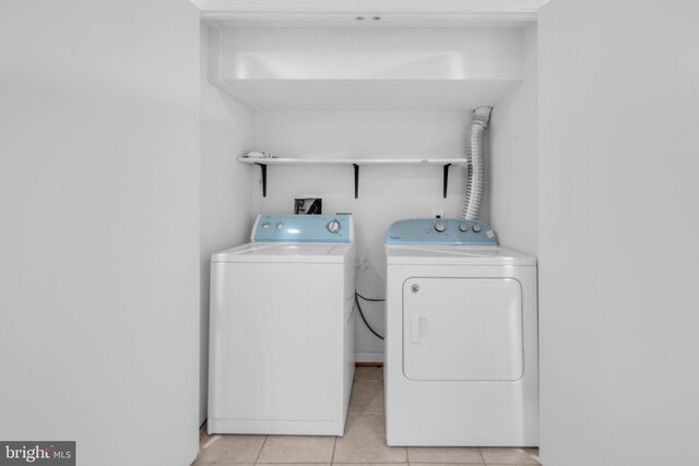 clothes washing area featuring washing machine and dryer and light tile patterned floors