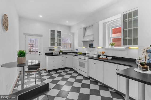 kitchen featuring gas range gas stove, healthy amount of natural light, dark countertops, dark floors, and recessed lighting