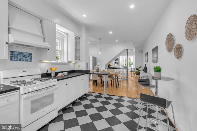 kitchen with white appliances, white cabinetry, recessed lighting, dark countertops, and tasteful backsplash