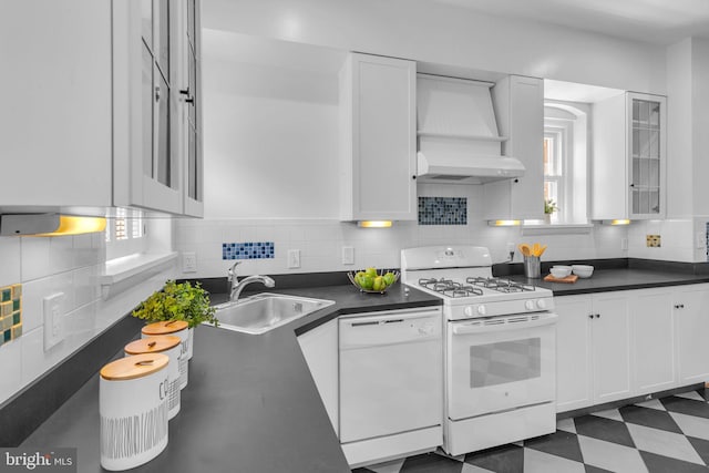 kitchen with white appliances, custom range hood, a sink, dark countertops, and white cabinetry