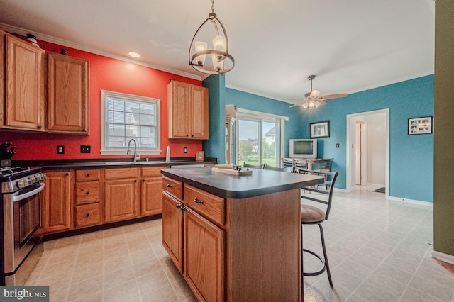 kitchen featuring dark countertops, stainless steel gas range oven, a sink, and crown molding