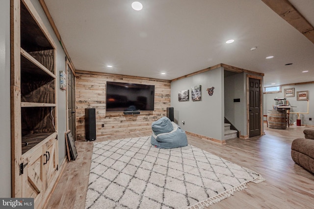 living room featuring light wood finished floors, stairway, wood walls, baseboards, and recessed lighting