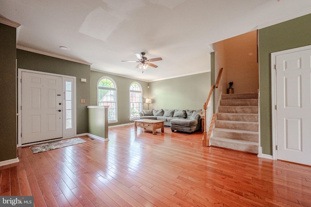 foyer entrance with baseboards, ornamental molding, light wood finished floors, and ceiling fan