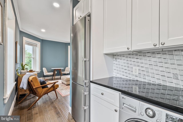 kitchen with high end fridge, washer / dryer, dark countertops, ornamental molding, and dark wood-style flooring