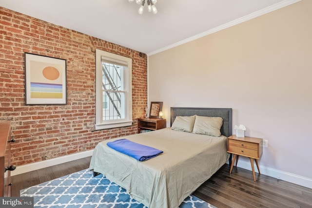 bedroom featuring baseboards, wood finished floors, ornamental molding, and brick wall