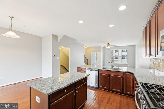 kitchen featuring stainless steel appliances, a peninsula, a sink, dark wood-style floors, and recessed lighting