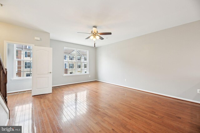spare room with a ceiling fan, light wood-style floors, and baseboards