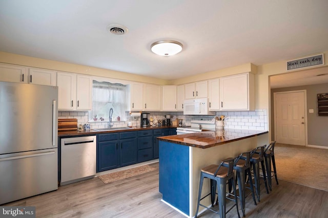 627 Ash St, Strasburg, VA 22657 - kitchen with stainless steel appliances, a sink, blue cabinetry, white cabinetry, and a kitchen bar