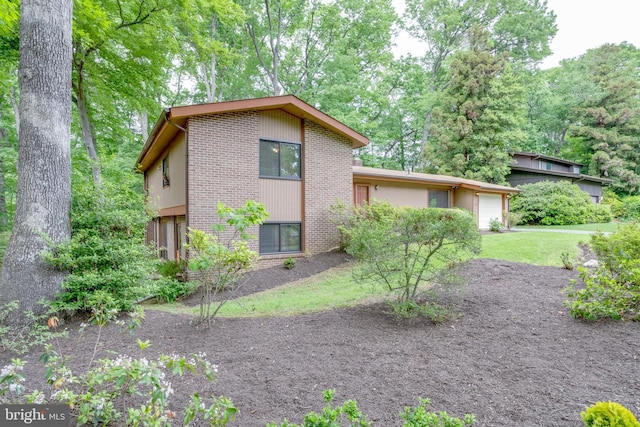 view of side of property with brick siding, an attached garage, and a yard