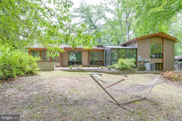 rear view of house with a sunroom and central AC