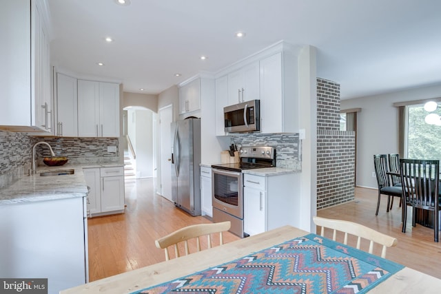 kitchen with stainless steel appliances, a sink, light wood-type flooring, white cabinetry, and recessed lighting
