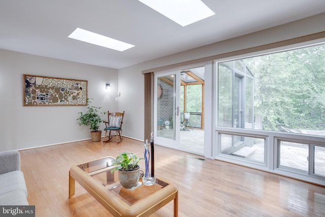 living room featuring a skylight and light wood-style floors