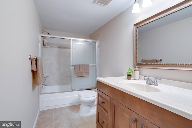 bathroom featuring toilet, vanity, tile patterned flooring, combined bath / shower with glass door, and baseboards