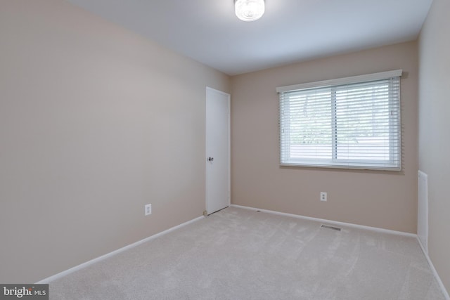 unfurnished room with light colored carpet and baseboards