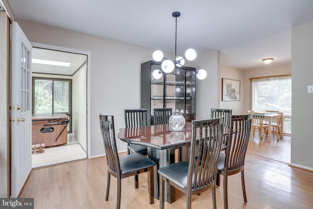 dining space featuring healthy amount of natural light, light wood-type flooring, and a chandelier
