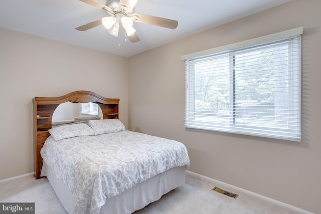 bedroom featuring light colored carpet, baseboards, and ceiling fan