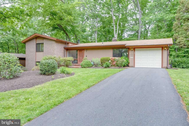 mid-century inspired home with a garage, asphalt driveway, a front lawn, and a chimney