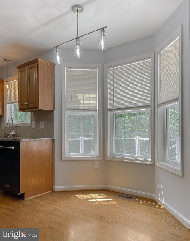 kitchen featuring light wood-style floors, baseboards, pendant lighting, and dishwasher