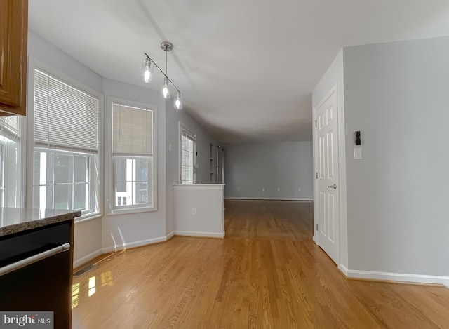 unfurnished dining area with light wood-type flooring and baseboards