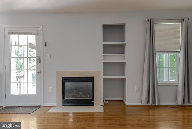 unfurnished living room with baseboards, a fireplace with flush hearth, and wood finished floors