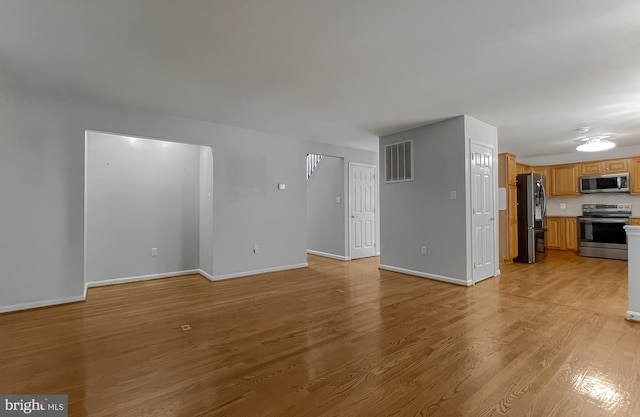 unfurnished living room with baseboards, light wood-type flooring, and visible vents