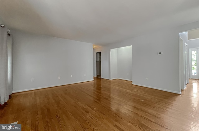 spare room featuring baseboards and wood finished floors