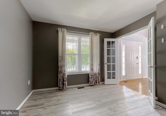 empty room featuring french doors, visible vents, wood finished floors, and baseboards