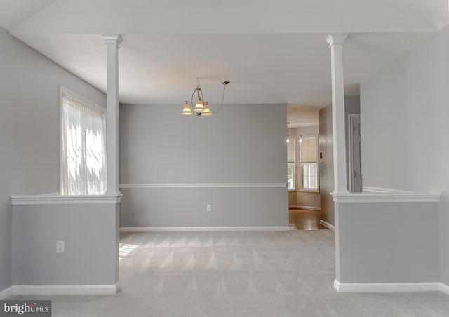 empty room featuring carpet flooring, baseboards, and ornate columns