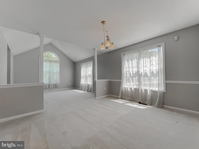 carpeted spare room featuring lofted ceiling, a notable chandelier, and baseboards