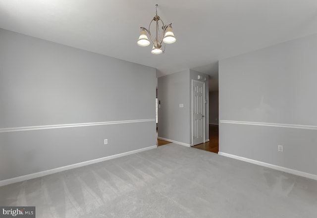 unfurnished room with baseboards, a chandelier, and carpet