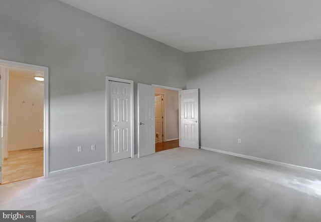 unfurnished bedroom featuring baseboards, a closet, and a towering ceiling