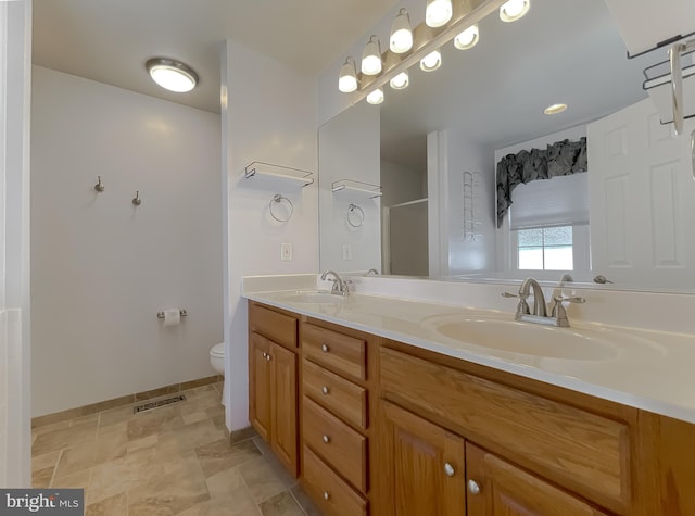 bathroom with a sink, double vanity, toilet, and visible vents