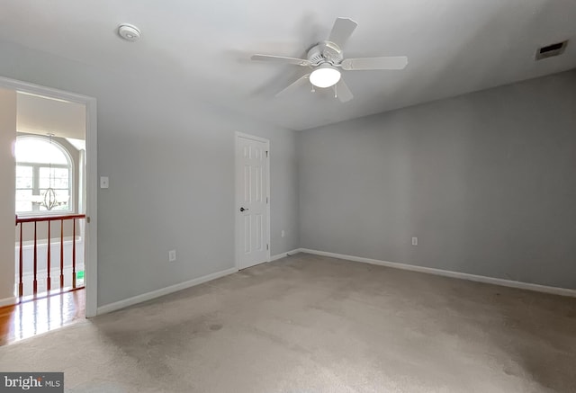 unfurnished room with light colored carpet, baseboards, a ceiling fan, and visible vents