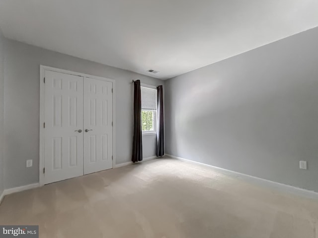 unfurnished bedroom featuring baseboards, carpet flooring, a closet, and visible vents
