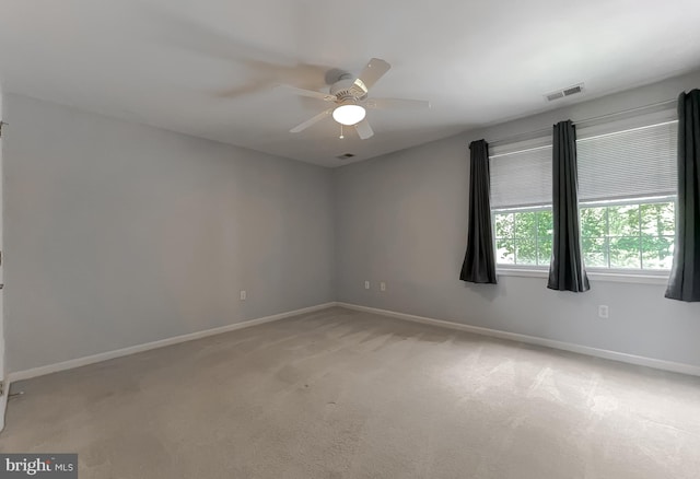 unfurnished room with ceiling fan, light carpet, baseboards, and visible vents