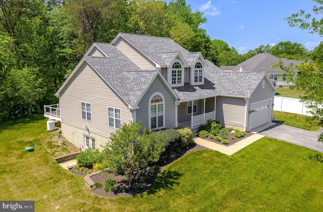 traditional-style home with roof with shingles, aphalt driveway, a front lawn, and an attached garage