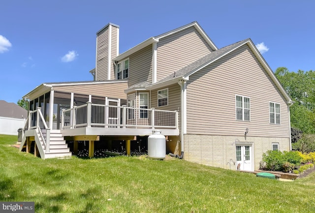 rear view of property with a sunroom, a yard, a chimney, and a deck