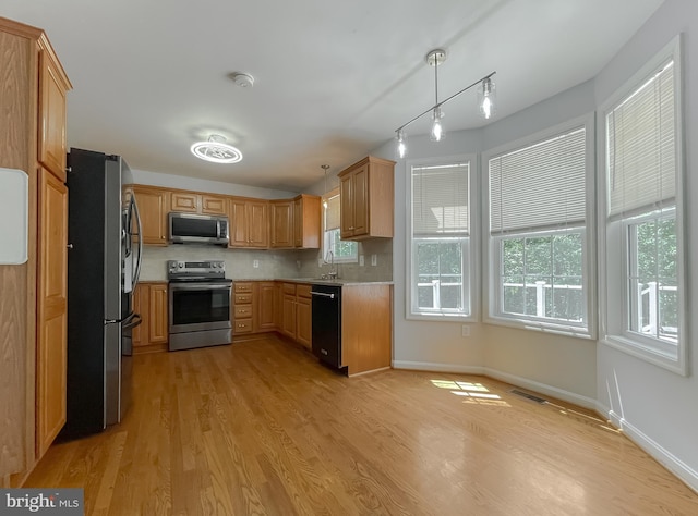 kitchen featuring a sink, track lighting, light wood-type flooring, light countertops, and appliances with stainless steel finishes