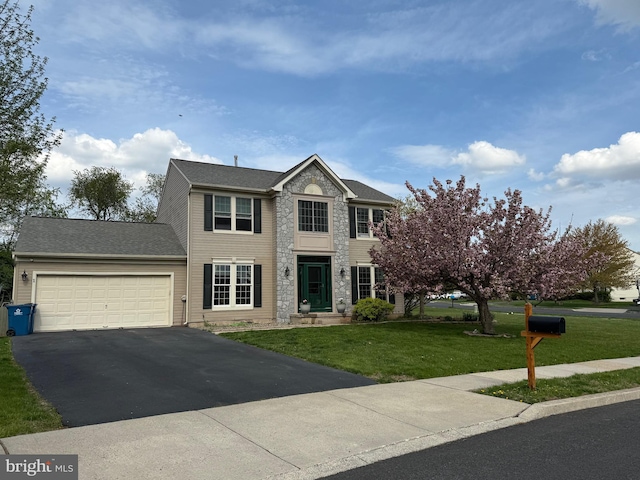 colonial inspired home with stone siding, a garage, driveway, and a front yard