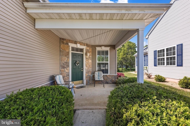 entrance to property with a porch and stone siding