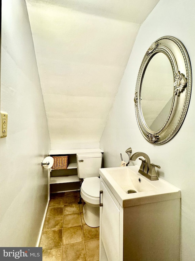 bathroom featuring toilet, vaulted ceiling, baseboards, and vanity