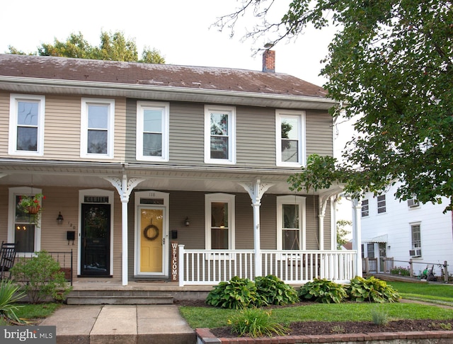view of front facade with covered porch and a chimney